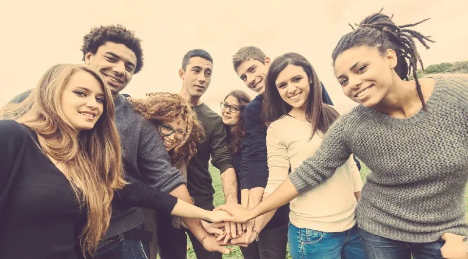 A group of young people with their hands joined in the middle